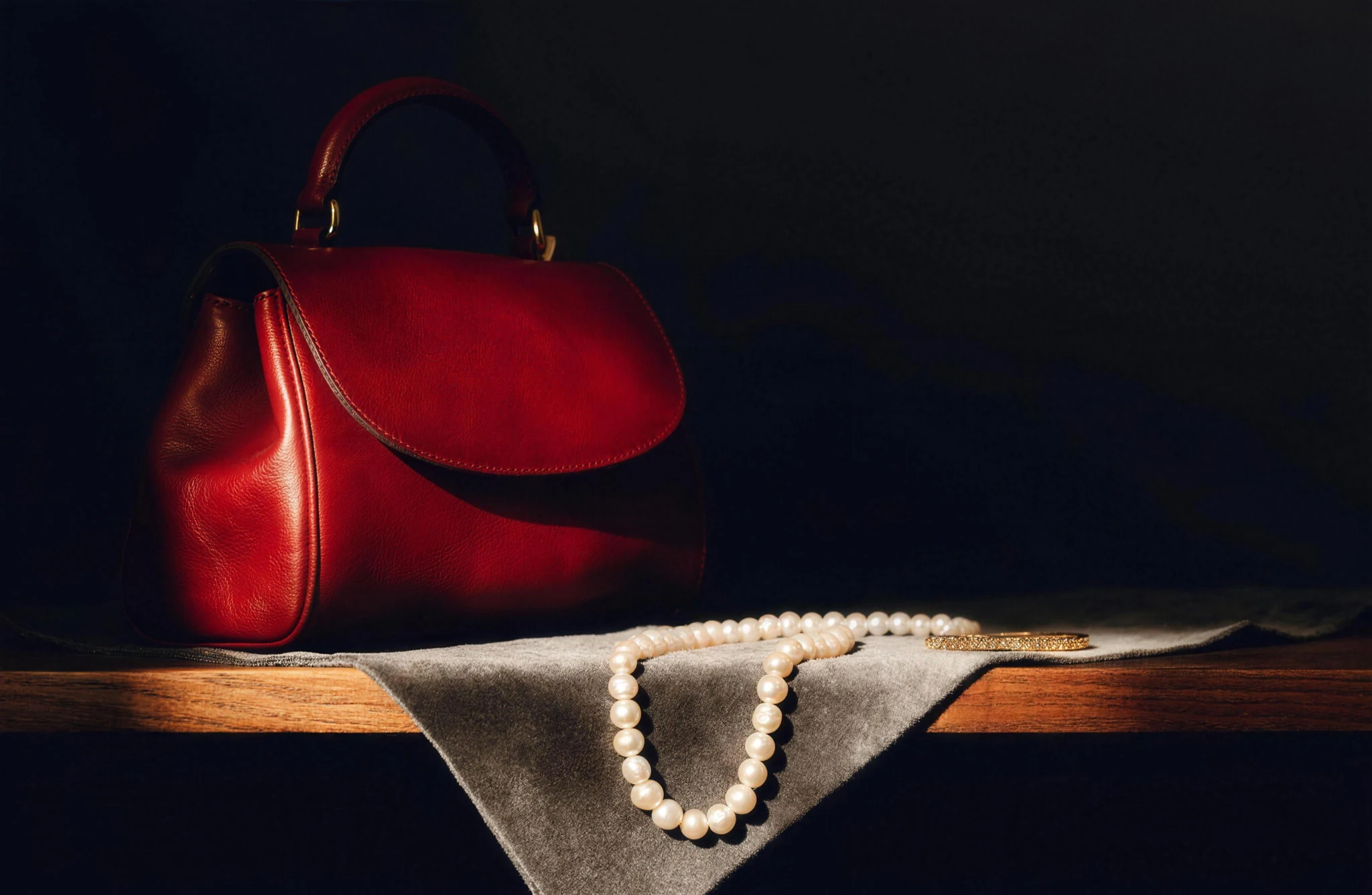 Burgundy leather handbag with pearls and gold jewellery