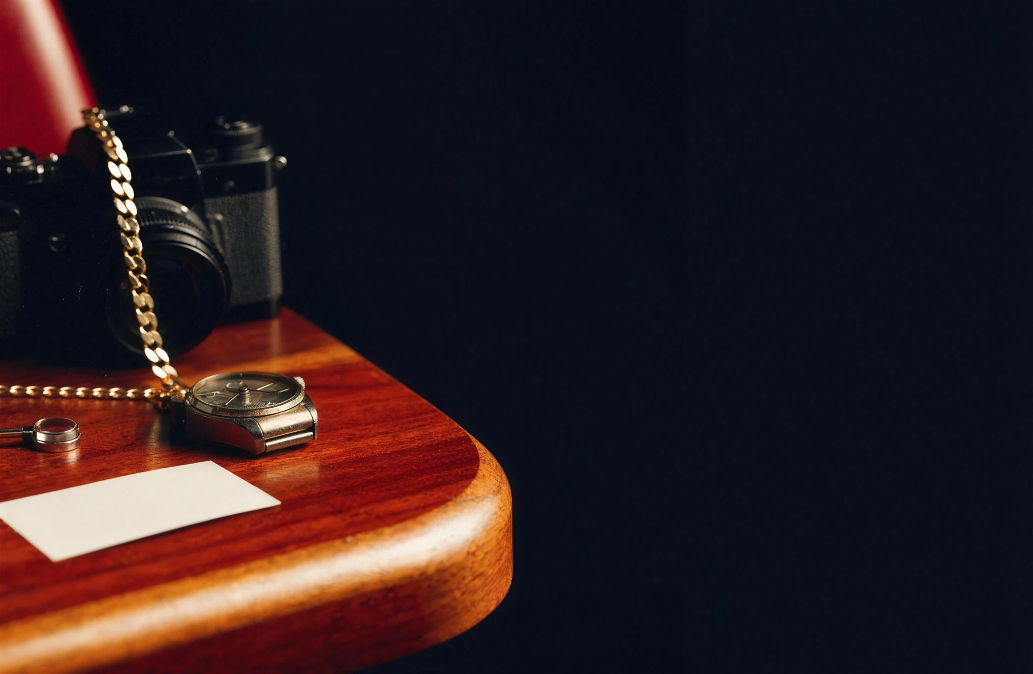 Watch, gold chain and camera on a timber valuation counter